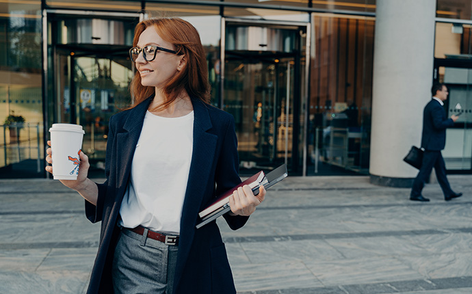Woman walking with tablet holding coffee in a city setting