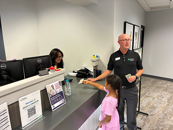 Child making her first savings deposit during a visit at the AdelFi branch with her family.